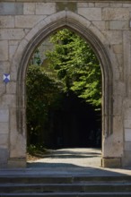 Historic stone gate with a view of a shady garden area behind it, Regensburg, Bavaria, Germany