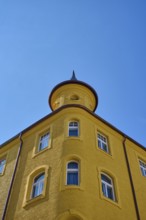 Yellow building with round tower and windows in front of a clear sky, Regensburg, Bavaria, Germany