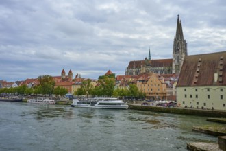 View of a cathedral and boats on a riverbank on a slightly cloudy day, Danube, Regensburg, Bavaria,