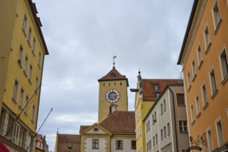 Street scene with a striking tower between historic buildings on a cloudy day, Regensburg, Bavaria,