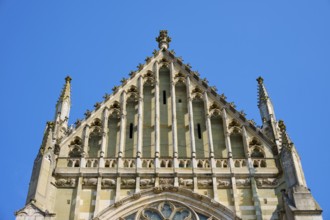 Decorated Gothic façade with window and roof spire under a clear sky, St Peter's Cathedral,
