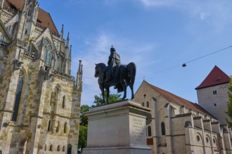 Equestrian statue in front of a historic church under a blue sky, St Peter's Cathedral, Regensburg,