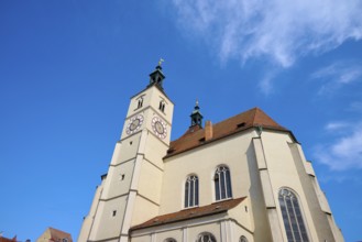 View of a church with a prominent steeple and clock against a clear blue sky, Neupfarrkirche,