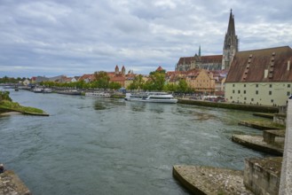 Panorama of a city with cathedral on the riverbank in a cloudy sky, Stone Bridge, Danube,