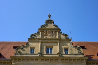 Baroque building front with sculptures and decorative stone ornaments under a clear sky, district
