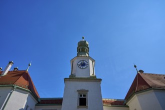 Tower with clock on a historic building. Blue roof and baroque details against a clear sky,
