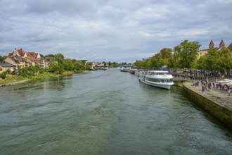 River landscape with boats and houses along the shore under a cloudy sky, Danube, Regensburg,