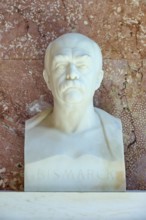 Marble bust of Bismarck against a red background, conveying seriousness and historical