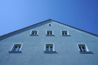 Blue house with several windows and sloping roof in front of a bright blue sky, Regensburg,