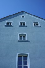 Facade of a blue house with symmetrical windows under a blue sky, Regensburg, Bavaria, Germany