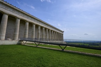 Historic columned building next to a green area under a clear blue sky, Walhalla, Donaustauf,