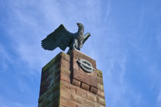 Close-up of an eagle on a stone monument in front of a clear blue sky. Radiance of majesty and