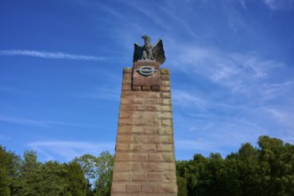 Massive stone monument with eagle, under a bright blue sky. Impression of grandeur and freedom in