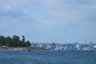Boats and yacht on the sea near a tree-covered shore with people, Windjammer Parade Kiel 2025,