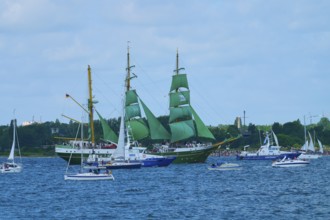 A large sailing ship with green sails Alexander von Humbold 2 and other boats on blue water,