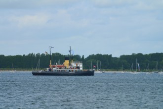 Icebreaker Stettin on a calm sea with several sailing boats and a cloudy sky, Windjammer Parade