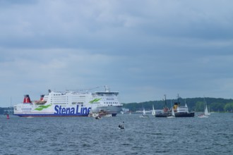 Stena Line ferry and historic ship in a sea travelled by sailing boats with cloudy sky, Windjammer