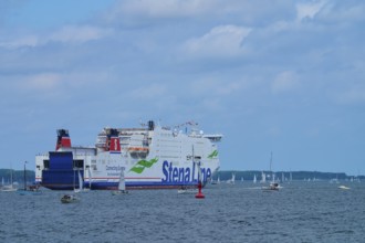 Large ferry on the sea surrounded by sailing boats under a slightly cloudy sky, Windjammer Parade