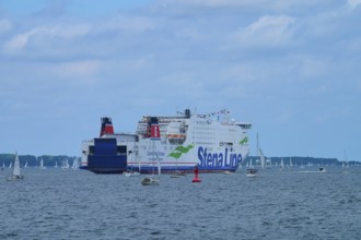 Large ferry on the sea surrounded by sailing boats under a blue sky, Windjammer Parade Kiel 2025,