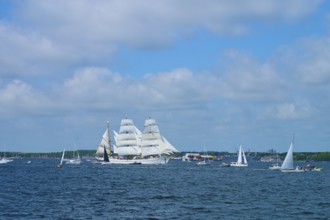 A magnificent tall ship Gorch Fock with white sails in a field of boats, Windjammer Parade Kiel