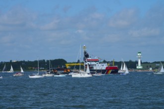 Large ship Arkona Coast Guard and numerous smaller sailing boats in the water in front of a