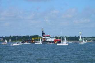 Various boats and a large ship Arkona Coast Guard on the sea next to a lighthouse Friedrichsort,