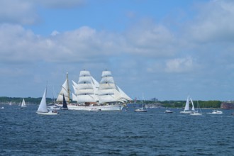 A large sailing ship Gorch Fock surrounded by smaller boats on the water, Windjammer Parade Kiel