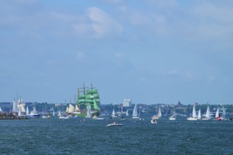 Green tall ship Alexander von Humbold 2 among many boats near a town, Windjammer Parade Kiel 2025,