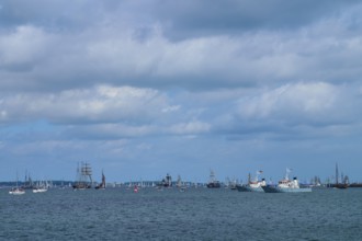 Yachts and sailing ships join each other on the sea under a cloudy sky, Windjammer Parade Kiel