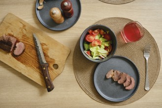 Slices of succulent duck breast are laid out on a cutting board beside a vibrant salad filled with