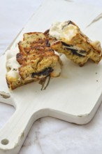 A delicious three cheese sandwich on a wooden cutting board, showcasing melted cheese and toasted