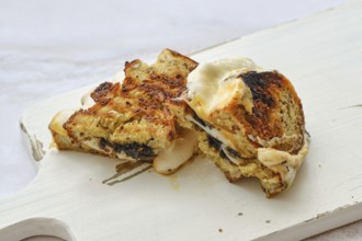 Cheese melts and blends together in a delightful three cheese sandwich resting on a rustic wooden