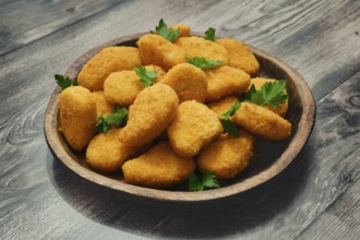 A generous portion of golden chicken nuggets is neatly arranged in a wooden bowl, garnished with