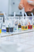 Several glasses on a table filled with colourful liquids and pipettes ready for an experiment,