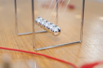 Swinging Newton pendulum on a wooden table shows movement and physical laws, Youth Research Centre