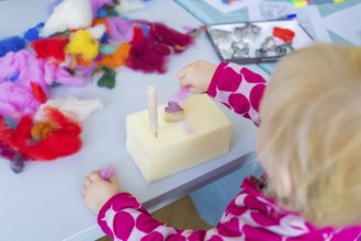 Child doing creative handicrafts with colourful wool and shapes at the table, Youth Research Centre