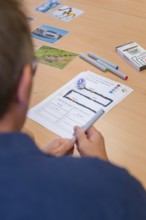Man plans or documents on paper with markers and small robot on a table, Youth Research Centre