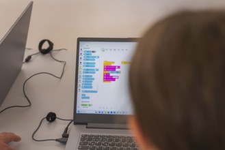 Two people working on laptops with a colourful programming interface, Youth Research Centre