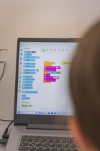 Person looking at a colourful programming interface on a laptop screen, Youth Research Centre