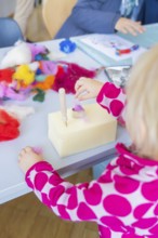 Creative moment: Child tinkering with colourful wool and tools, Youth Research Centre