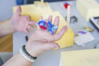 Person holding a colourful piece of foam while crafting with different materials, Youth Research