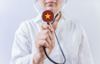 Female doctor holding stethoscope with Vietnam flag. National health system of Vietnam