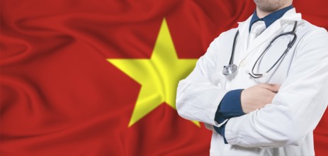 Vietnam healthcare concept. Male doctor on Vietnam flag. Doctor with crossed arms on Vietnam flag