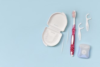 Top view of dental clear aligners, toothbrush, toothpicks and floss on blue background with copy