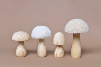 Four wooden mushroom ornaments in a row on beige background