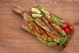 Fried crispy red mullet fish, on a wooden chopping board, with lime, no people