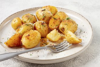 Half-eaten fried new potatoes, with butter and dill, on a white plate, with a fork, at home, no