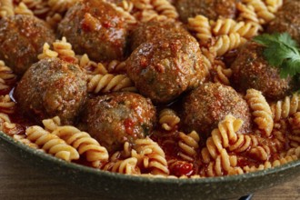 Minced meat meatballs, in tomato sauce, with fusilli pasta, in a cast-iron pan, homemade, no people