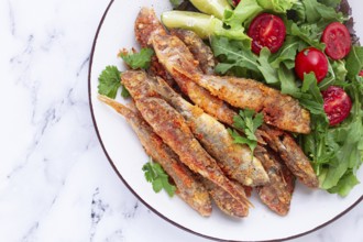 Fried crispy mullet fish, with fresh salad, on a plate with lime, no people