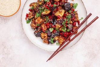 Fried eggplant, Chinese style, in sweet and sour sauce, with pepper and sesame seeds. on a white